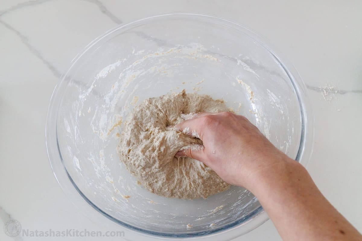 using hands to mix the sourdough bread dough