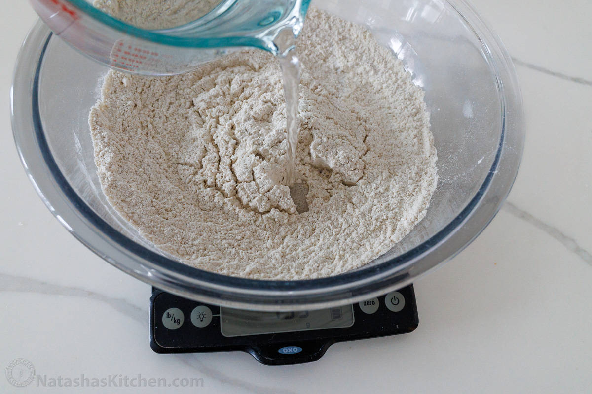 Adding warm water to flour on a kitchen scale