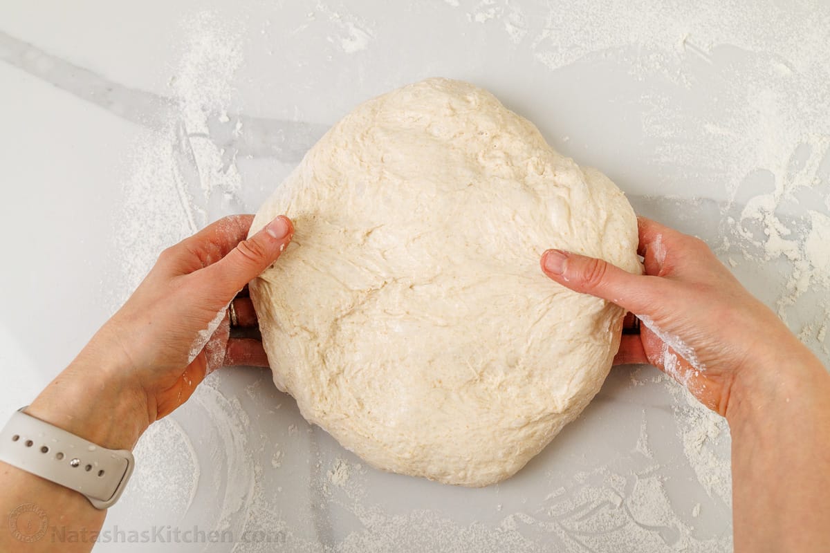 stretching the sourdough bread dough while shaping