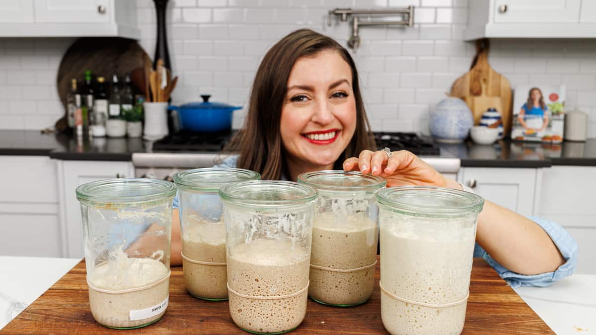 Natasha from Natashas Kitchen with jars of homemade sourdough in different growth stages