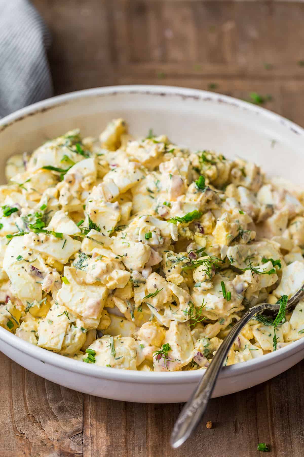 Quick Egg Salad in a serving bowl with a spoon and garnished with herbs,