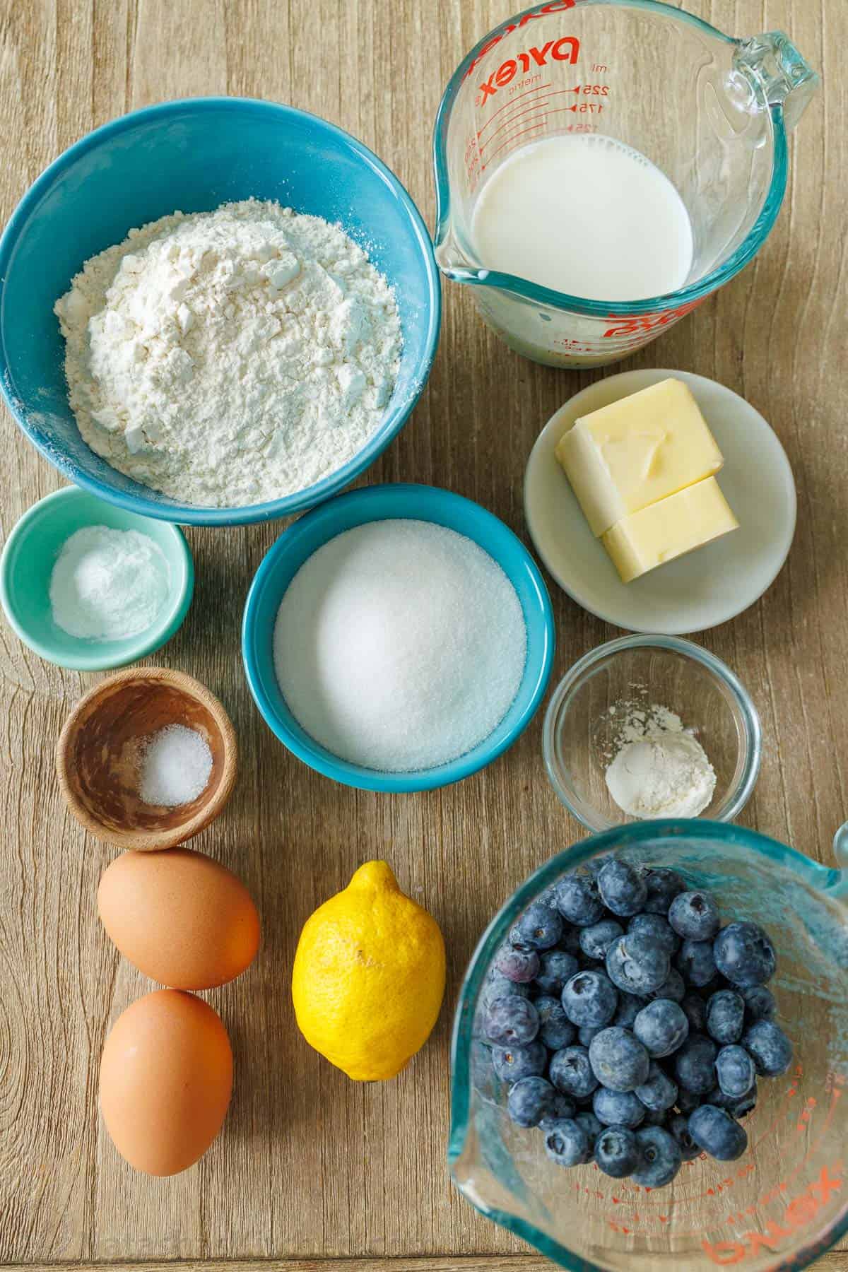 Ingredients for Blueberry Lemon Bread measured out. Blueberries, lemon, eggs, flour, sugar, butter, milk, baking powder, salt, vanilla