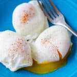 Poached eggs seasoned with paprika served on blue plate