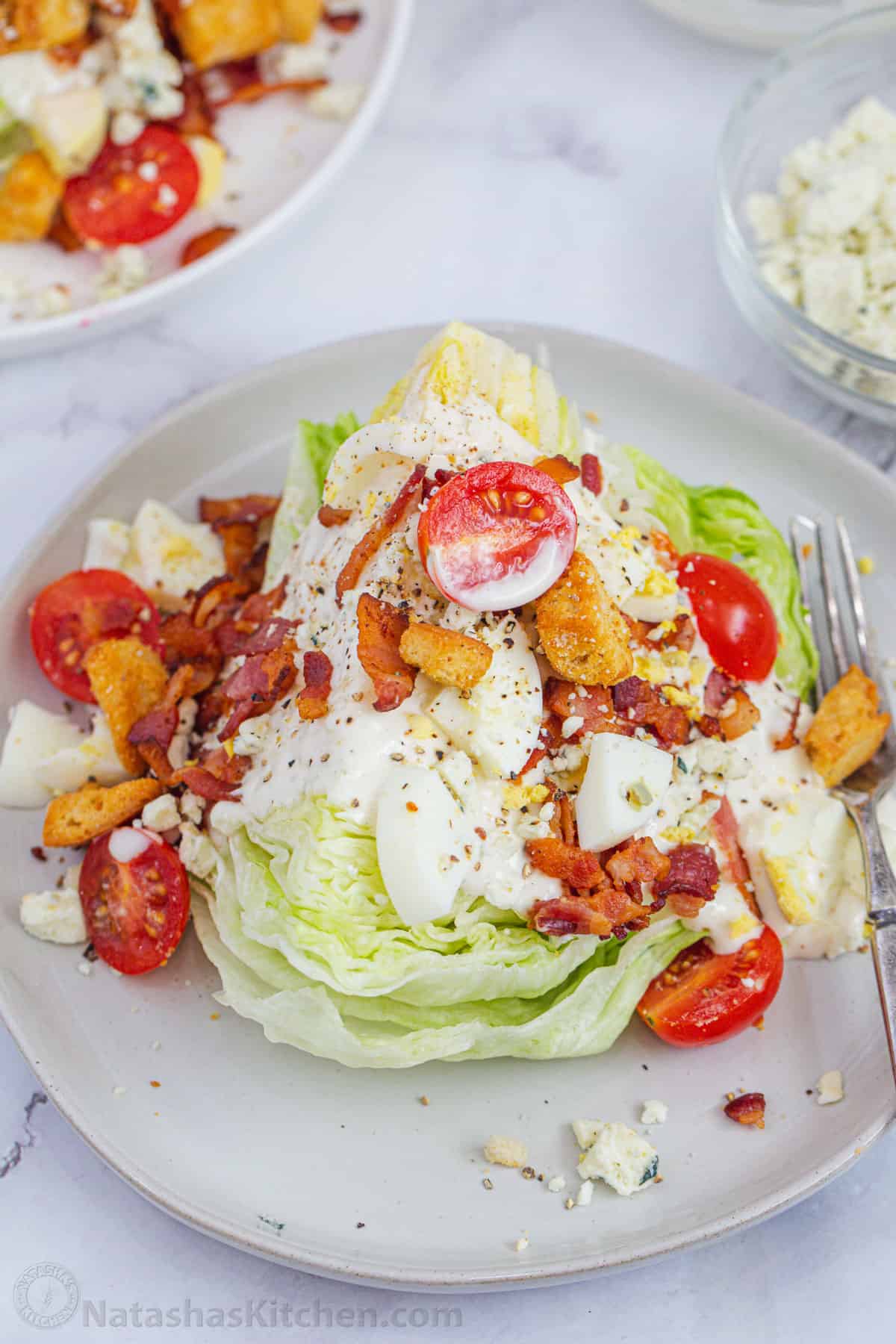 Closer up wedge of iceberg with dressing and toppings on a plate