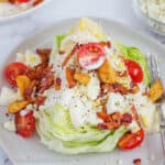 Wedge salad with dressing and toppings served on a white plate