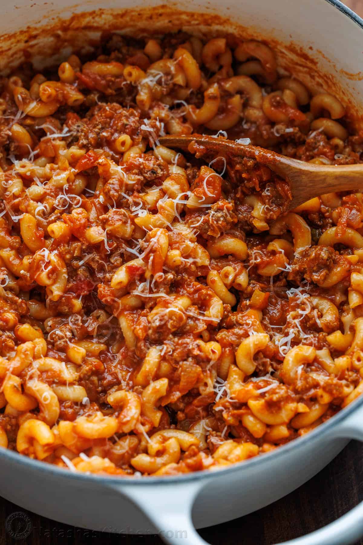 Goulash recipe stirred in a white dutch oven with wooden spoon