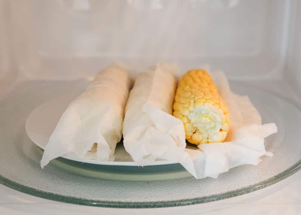 Corn on the cob wrapped in damp paper towels in microwave.