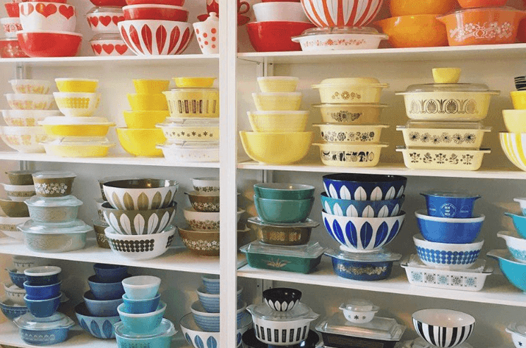 A large shelf containing a huge assortment of colorful vintage Pyrex