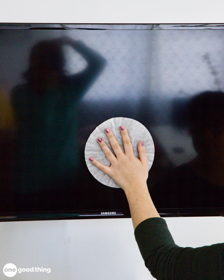 woman's hand using a coffee filter to dust a TV screen