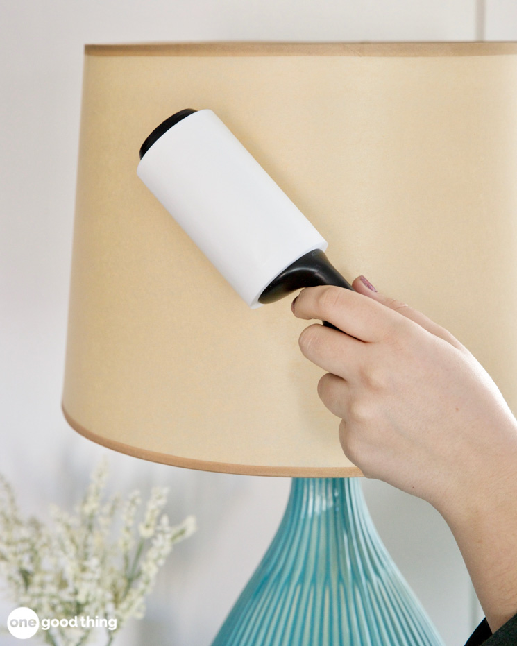 Woman's hand using a lint roller to dust a fabric lamp shade