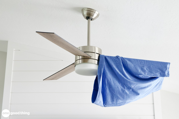 Stainless steel ceiling fan with a blue pillowcase over one blade