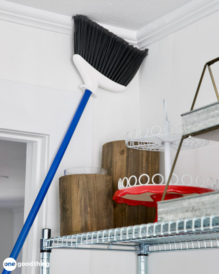 broom being used to dust corner of ceiling