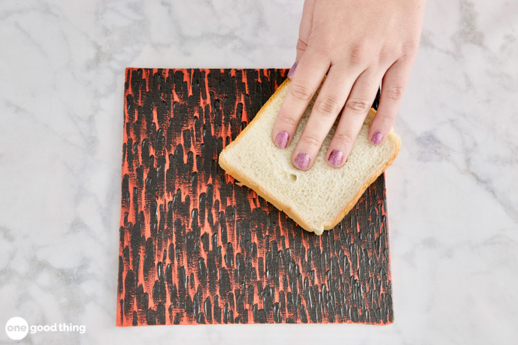 woman's hand using bread to clean a painting