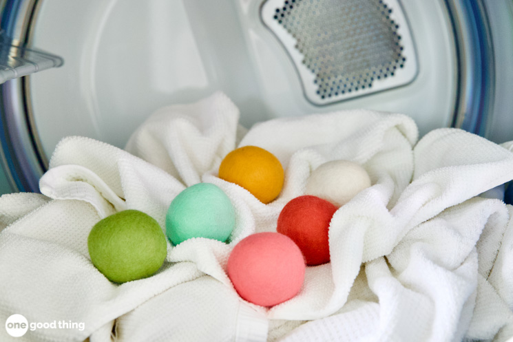 Solutions To Annoying Laundry Problems - colorful wool dryer balls in a dryer on top of fluffy white towels