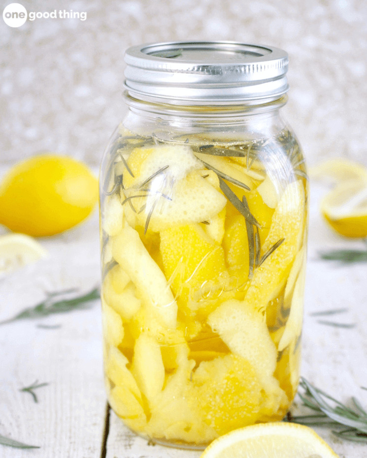 glass mason jar with lemon peels and rosemary in it sitting on a table