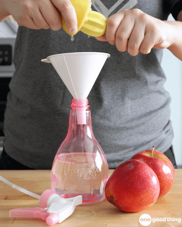 hands juicing a lemon into a white funnel that's in a pink plastic spray bottle