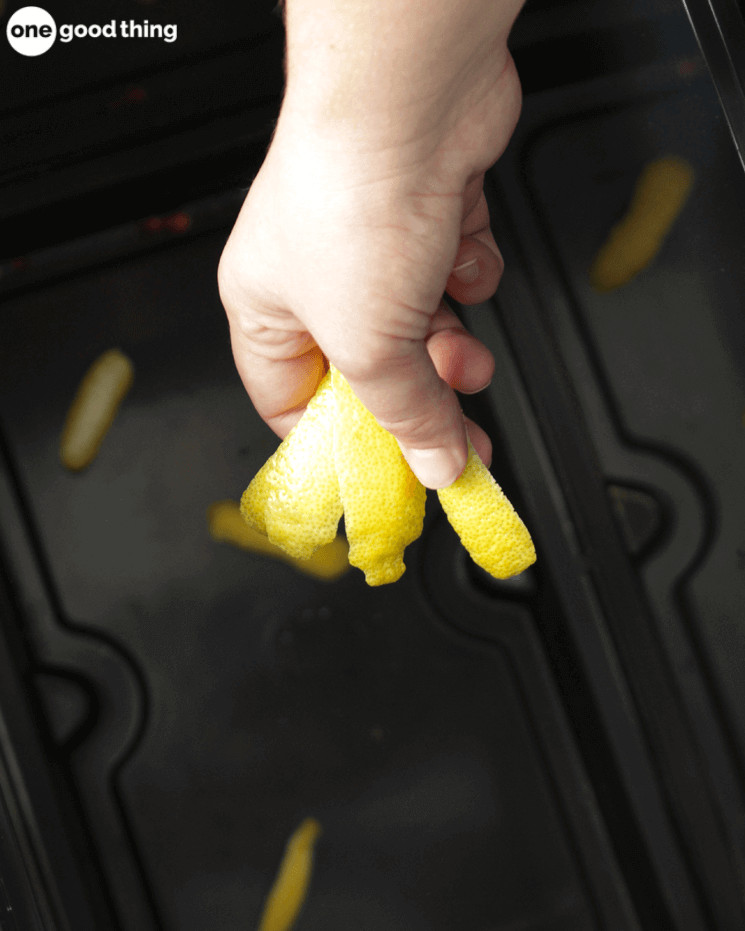 hand holding lemon peels over a black trashcan