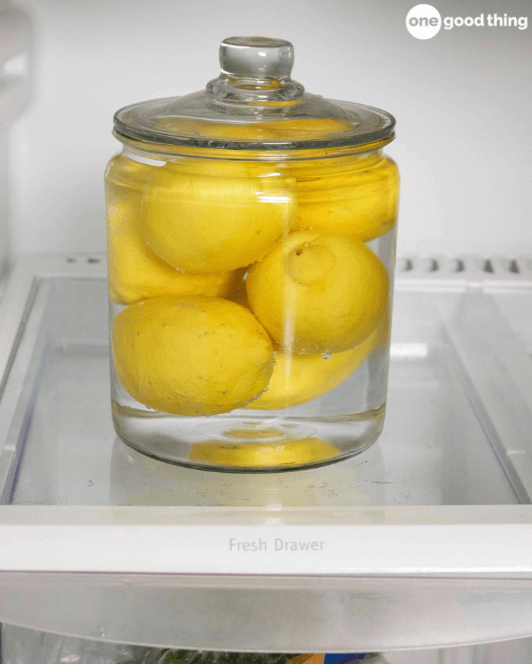 clear glass jar filled with water and lemons sitting on a fridge shelf