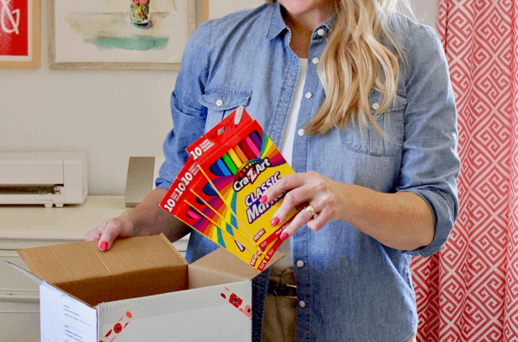 woman putting boxes of markers into a donation box